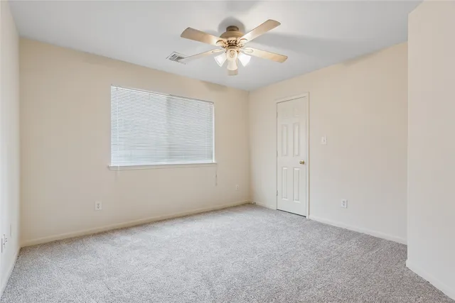 an empty room with windows and ceiling fan