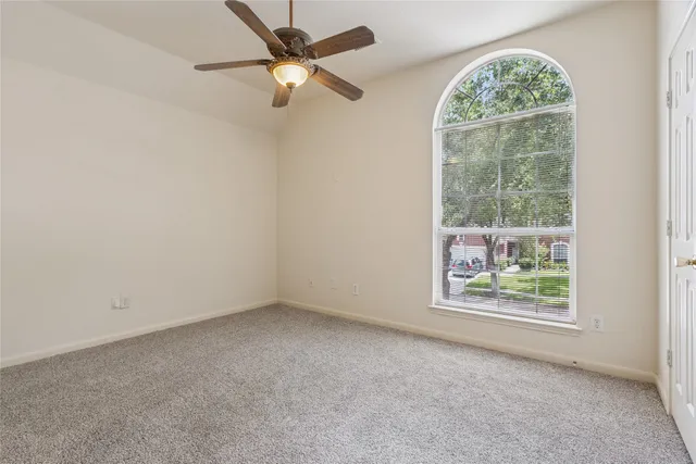 an empty room with windows and ceiling fan
