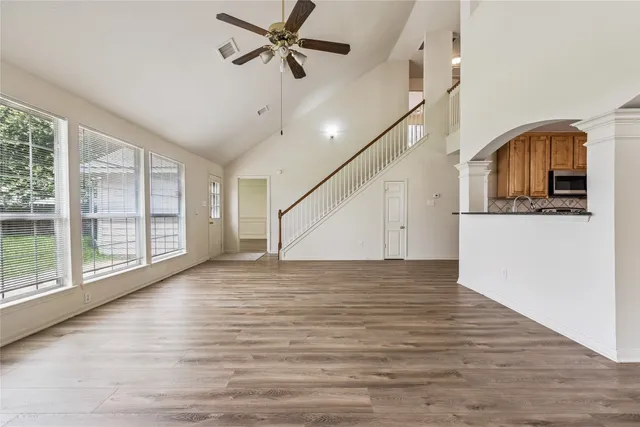 a view of empty room with wooden floor and fan