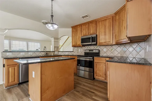 a kitchen with stainless steel appliances granite countertop a stove a sink and a microwave