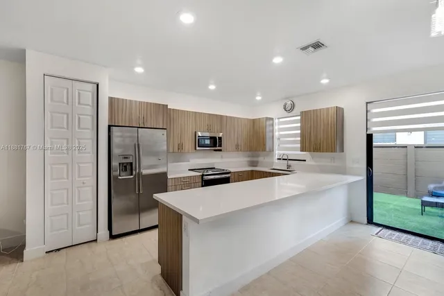a large kitchen with a large counter top stainless steel appliances and cabinets