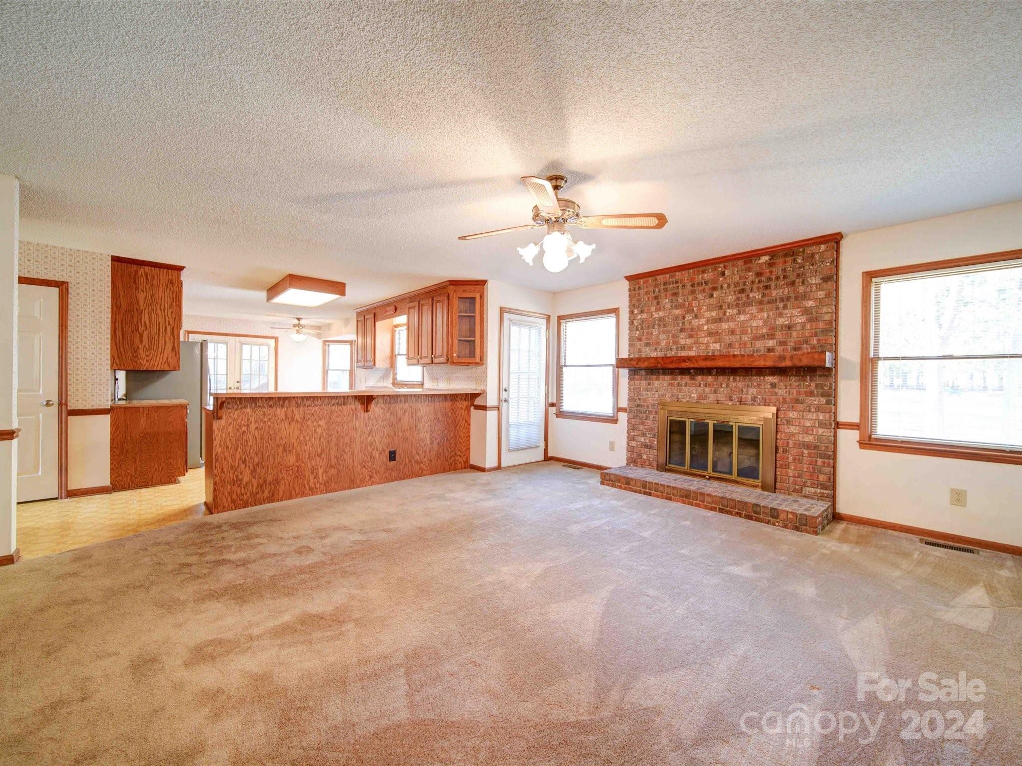 8426 Live Oak Road Harrisburg, NC 28075 - Photo 21 of 46 an empty room with windows fireplace and a kitchen