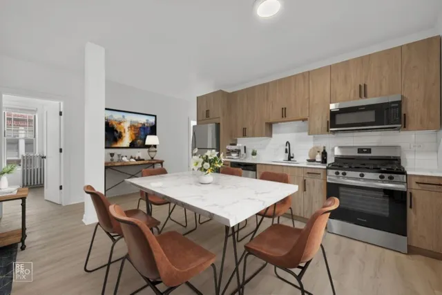 a kitchen with stainless steel appliances a stove top oven a sink dishwasher and a refrigerator with wooden floor