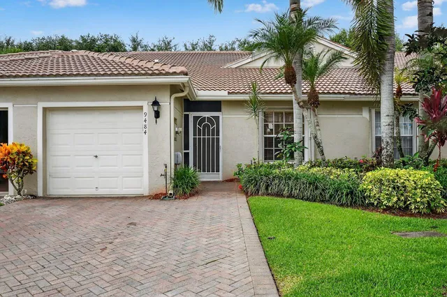 a front view of a house with a garden and palm tree