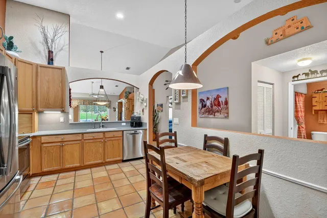 a kitchen with stainless steel appliances granite countertop a sink a stove a refrigerator cabinets and dining table