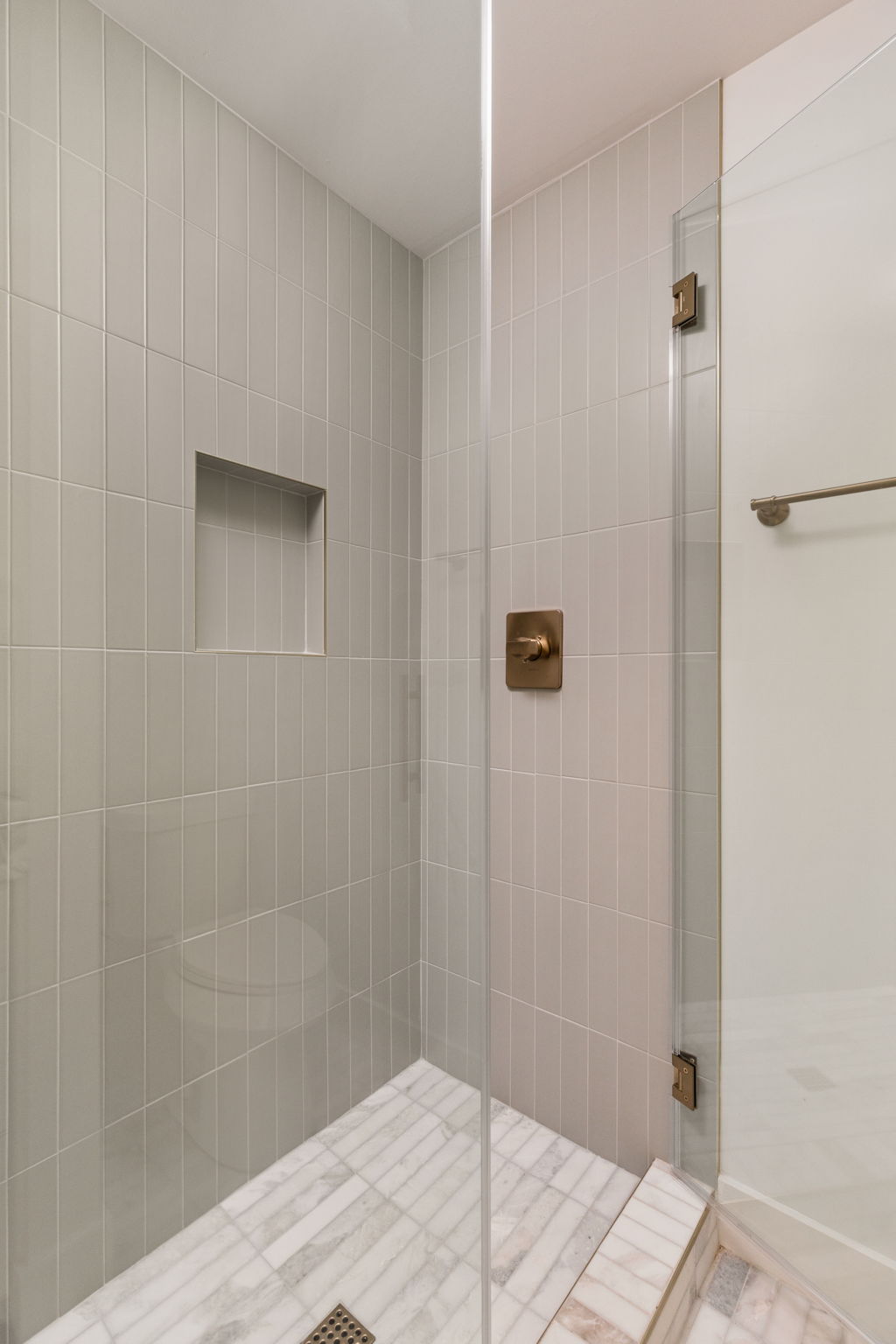 4501 Pack Saddle Pass Austin, TX 78745 - Photo 21 of 37 Shower stall featuring light gray vertical subway tile, a recessed niche, clear glass enclosure, and bronze-finish hardware