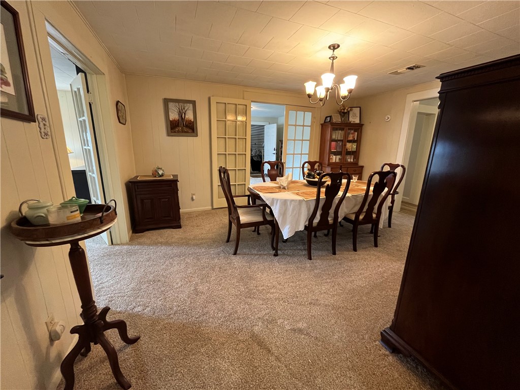 1102 North Travis Avenue Cameron, TX 76520 - Photo 14 of 48 Dining space with light colored carpet, a chandelier, and wood walls