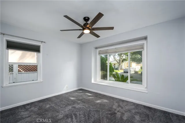 an empty room with windows and ceiling fan