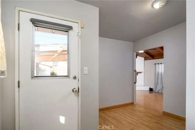 a view of an empty room with wooden floor and a window