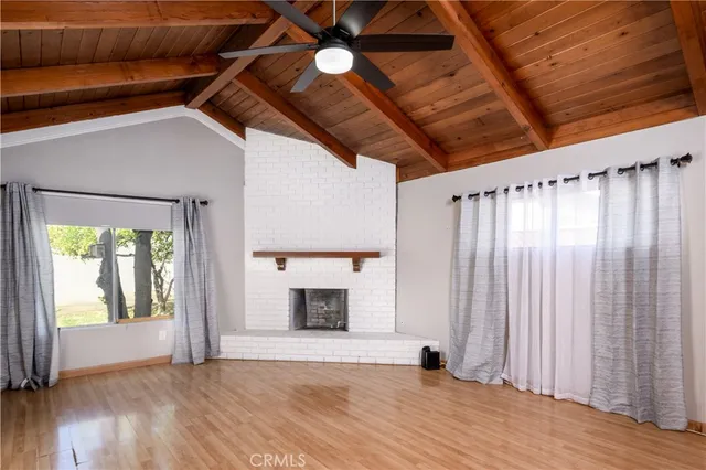 a view of an empty room with wooden floor fireplace and a window