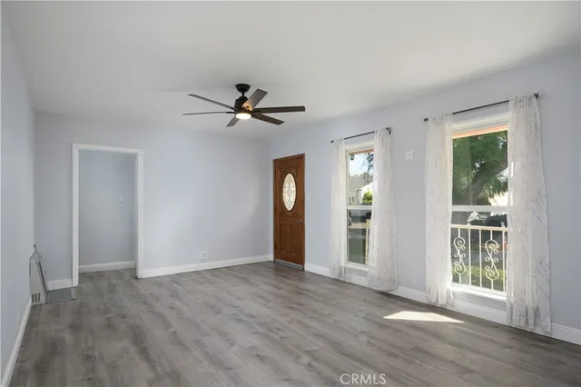 a view of an empty room with window and wooden floor