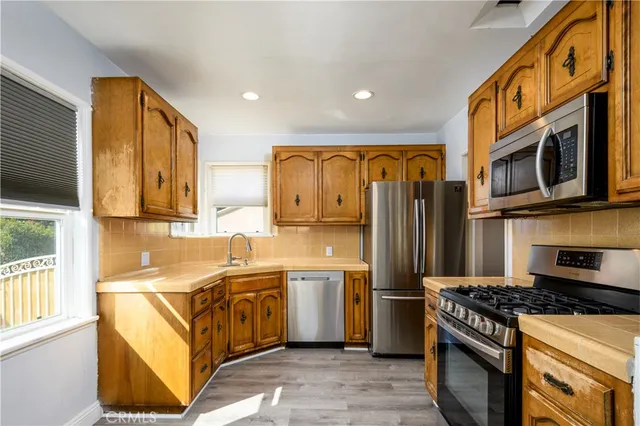 a kitchen with stainless steel appliances granite countertop a stove top oven a sink dishwasher and a refrigerator