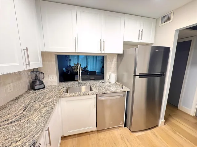 a kitchen with a refrigerator sink and cabinets