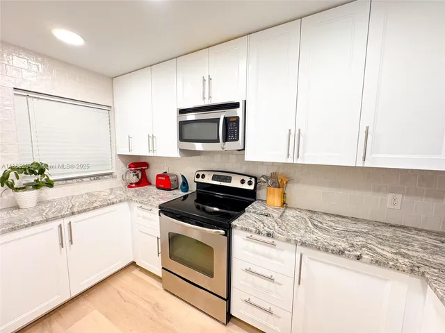 a kitchen with granite countertop white cabinets and white appliances