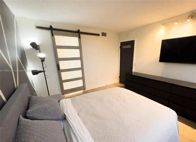 a bedroom with a bed and a flat tv screen on dresser