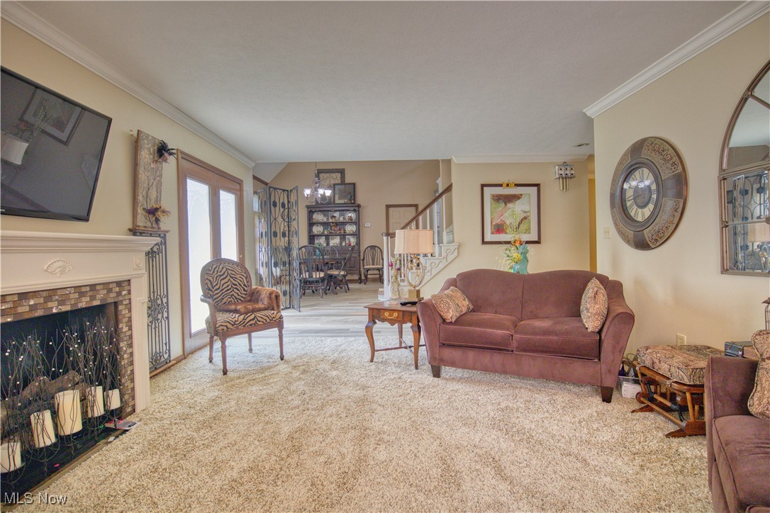 7017 Kirk Road Canfield, OH 44406 - Photo 12 of 35 Carpeted living area with a fireplace, crown molding, and stairway