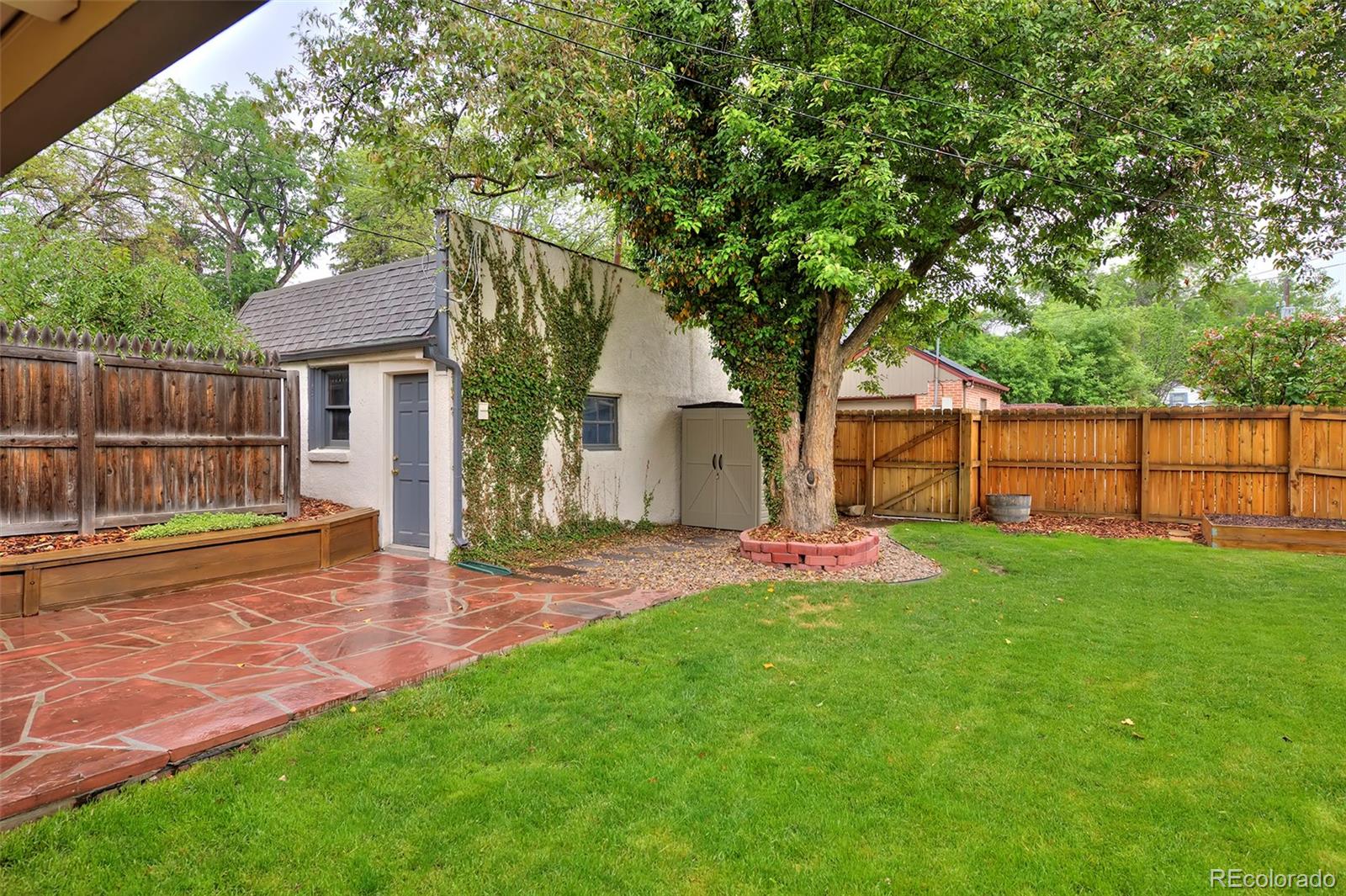 1674 Cherry Street Denver, CO 80220 - Photo 22 of 31 a view of a backyard with table and chairs and wooden fence