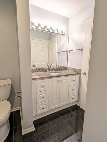 a bathroom with a granite countertop sink toilet and mirror