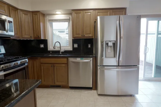 a kitchen with stainless steel appliances granite countertop a refrigerator a sink and white cabinets