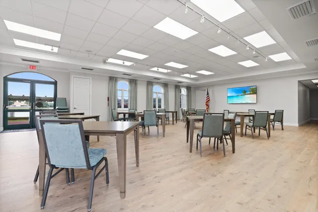 a dining hall with stainless steel appliances a dining table and chairs with the view of kitchen