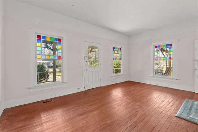an empty room with wooden floor fireplace and windows