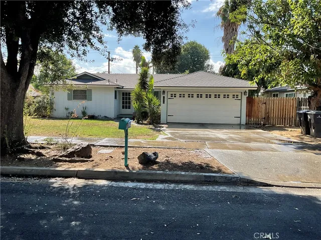 a view of a house with a yard and large tree