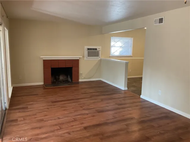 a view of empty room with wooden floor and fireplace