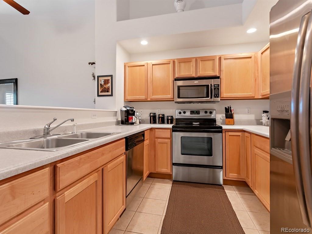 5800 Tower Road, Unit 908 Denver, CO 80249 - Photo 6 of 25 a kitchen with stainless steel appliances granite countertop a stove top oven a sink and a refrigerator