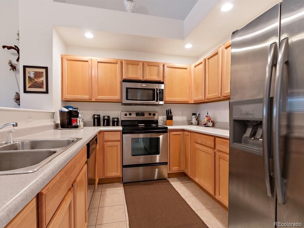 5800 Tower Road, Unit 908 Denver, CO 80249 - Photo 7 of 25 a kitchen with a sink cabinets and stainless steel appliances