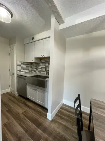 a kitchen with stainless steel appliances a stove a sink and white cabinets with wooden floors