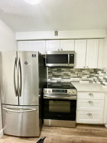 a kitchen with stainless steel appliances granite countertop a refrigerator and a stove top oven