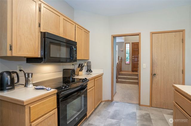 a kitchen with stainless steel appliances granite countertop a stove oven a dining table and chairs with wooden floor