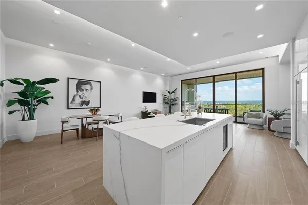 a large white kitchen with a large window and furniture