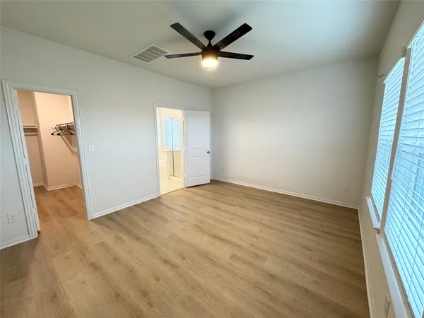 an empty room with a ceiling fan and wooden floor