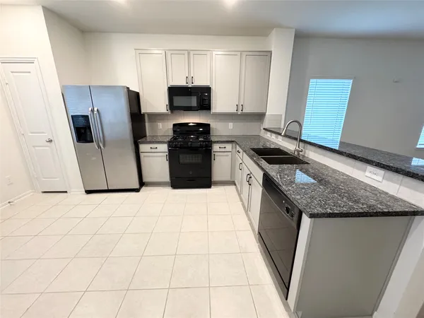 a kitchen with granite countertop a sink a stove and a microwave