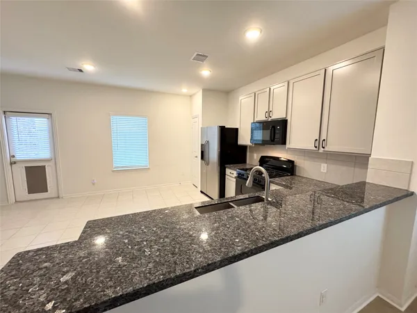 a kitchen with stainless steel appliances kitchen island granite countertop a stove a sink and a refrigerator