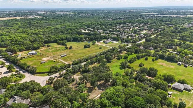 an aerial view of residential houses with outdoor space and trees