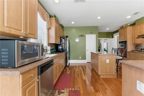 a large kitchen with stainless steel appliances sink a microwave and cabinets