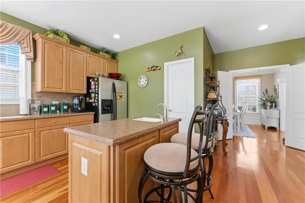 a kitchen with stainless steel appliances granite countertop a refrigerator a sink a stove and white cabinets
