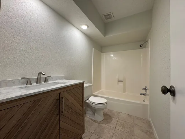 a bathroom with a granite countertop sink a toilet and shower