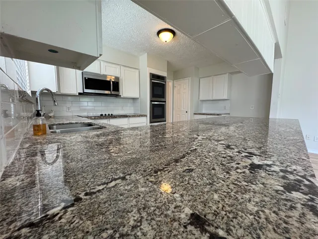 a kitchen with stainless steel appliances a sink a stove and cabinets