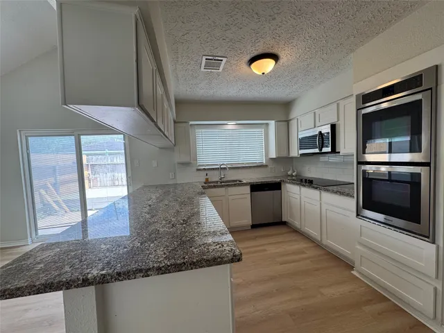 a kitchen with granite countertop a sink stainless steel appliances and cabinets