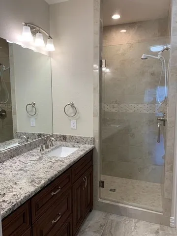 a bathroom with a granite countertop sink a shower and a mirror