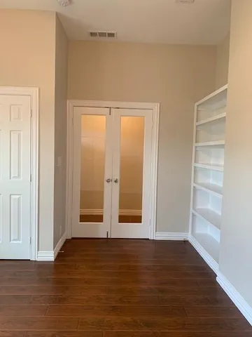 a view of an empty room with wooden floor and windows