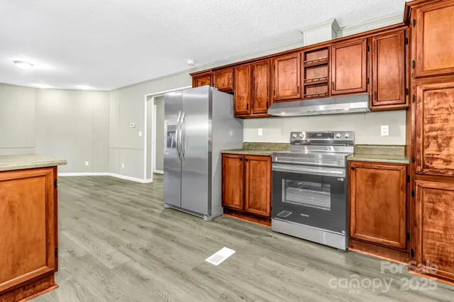a kitchen with stainless steel appliances granite countertop a refrigerator a stove and a sink