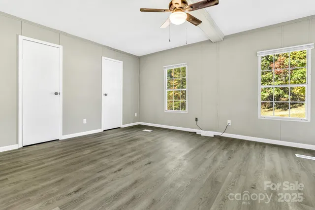 a view of an empty room with a window and wooden floor