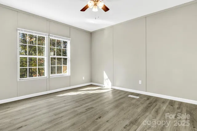 an empty room with wooden floor and windows