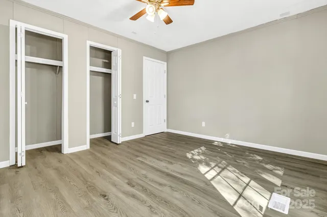 an empty room with wooden floor closet and windows