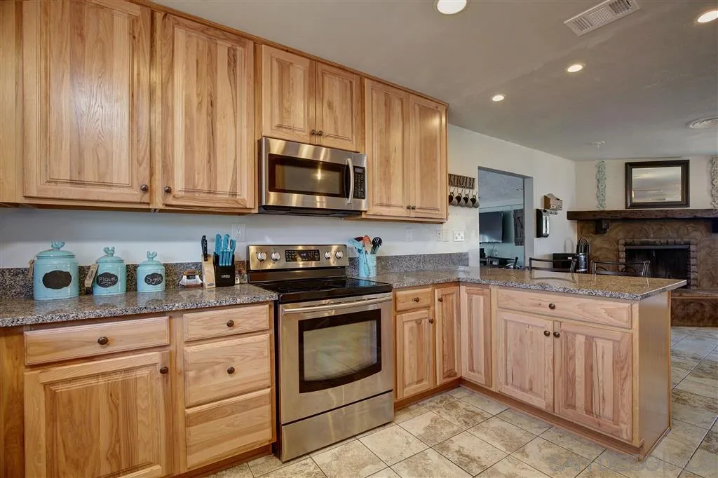 14558 Fruitvale Road Valley Center, CA 92082 - Photo 7 of 24 a kitchen with granite countertop a stove sink and cabinets