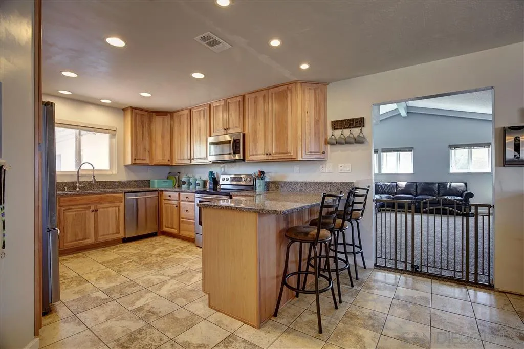 14558 Fruitvale Road Valley Center, CA 92082 - Photo 8 of 24 a kitchen with stainless steel appliances granite countertop a stove a sink a microwave a center island and furniture